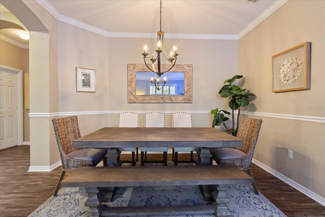 dining room featuring a chandelier, arched walkways, wood finished floors, baseboards, and ornamental molding