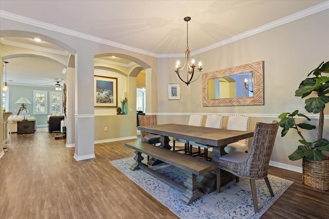 dining area with crown molding, arched walkways, and wood finished floors