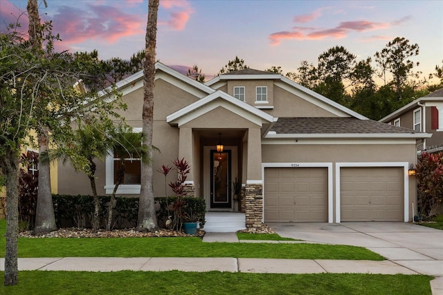 view of front facade featuring a lawn, a garage, stucco siding, concrete driveway, and roof with shingles