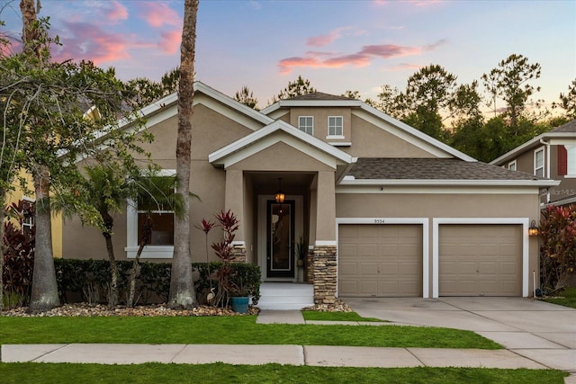craftsman-style home featuring stucco siding, concrete driveway, a garage, and a shingled roof