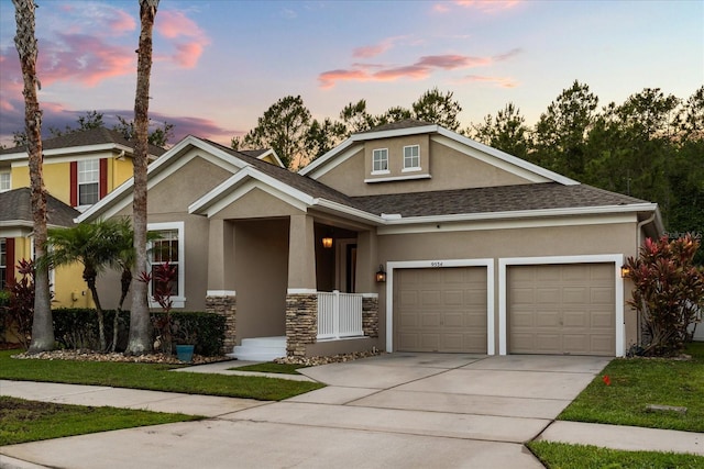 craftsman house with stucco siding, concrete driveway, a garage, stone siding, and roof with shingles