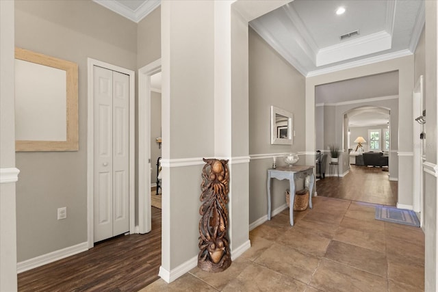 hall featuring arched walkways, crown molding, wood finished floors, and baseboards