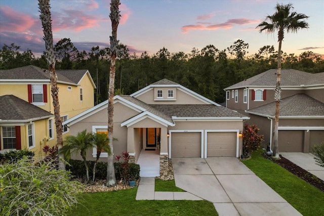 view of front of property with stucco siding, a garage, concrete driveway, a front yard, and a shingled roof