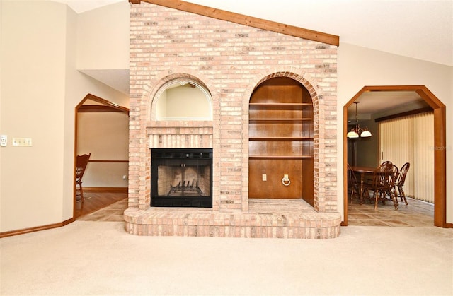 carpeted living room with vaulted ceiling, a fireplace, built in features, and baseboards