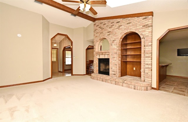unfurnished living room with a ceiling fan, carpet, built in shelves, baseboards, and a fireplace
