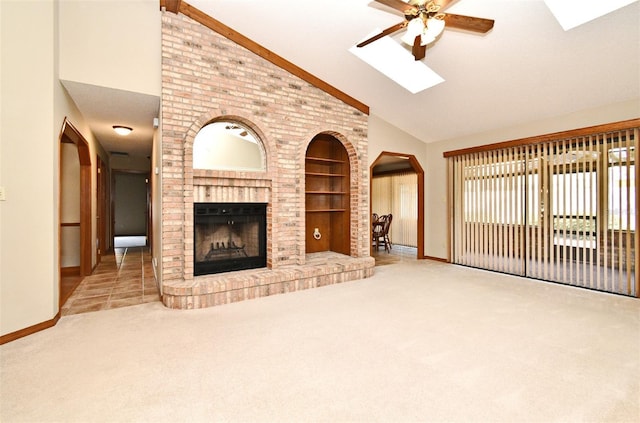 unfurnished living room with a skylight, built in features, a ceiling fan, high vaulted ceiling, and baseboards