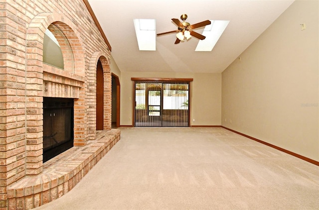 unfurnished living room with a skylight, carpet flooring, a fireplace, lofted ceiling, and a ceiling fan