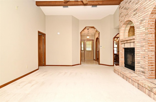 unfurnished living room featuring carpet, baseboards, a fireplace, arched walkways, and beamed ceiling