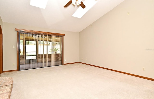 carpeted spare room featuring a ceiling fan, a skylight, lofted ceiling, and baseboards