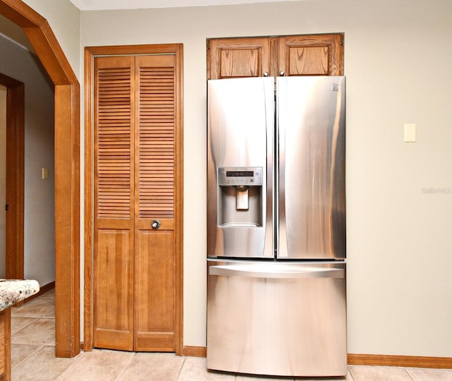 kitchen featuring stainless steel refrigerator with ice dispenser, baseboards, and light tile patterned floors