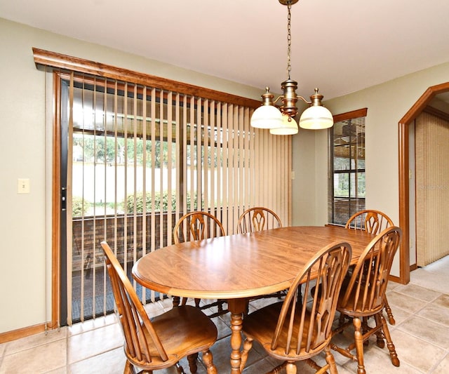 dining area featuring baseboards, a chandelier, arched walkways, and light tile patterned floors