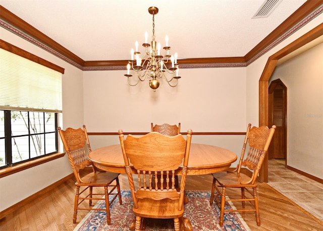 dining area with ornamental molding, a chandelier, baseboards, arched walkways, and wood finished floors