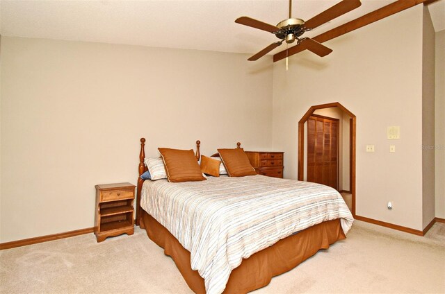 bedroom with light carpet, baseboards, vaulted ceiling, arched walkways, and a ceiling fan