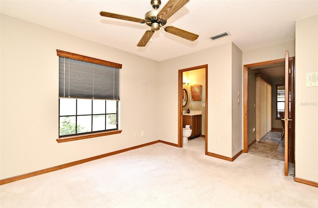 spare room with plenty of natural light, baseboards, light colored carpet, and a ceiling fan