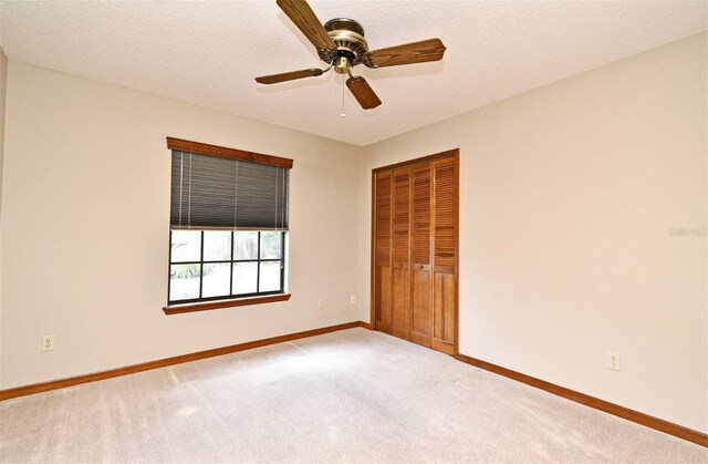 carpeted spare room featuring baseboards and ceiling fan