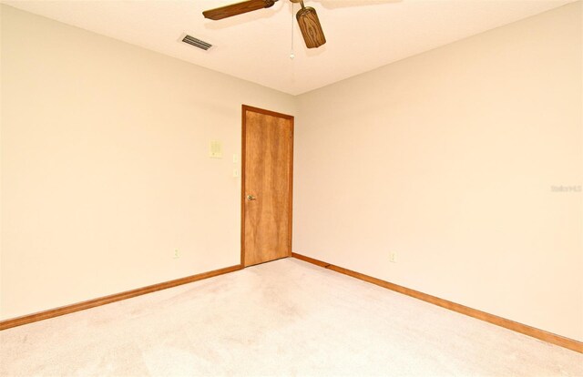spare room featuring light carpet, baseboards, and a ceiling fan