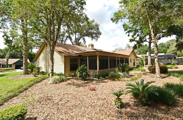 rear view of property featuring a chimney, a sunroom, and fence
