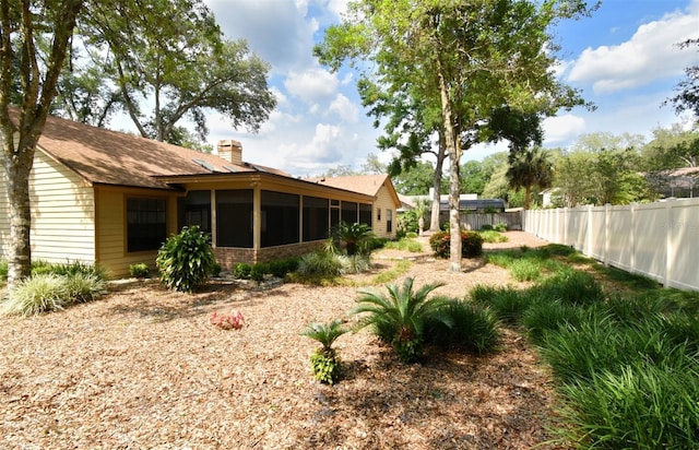 back of property with fence, a sunroom, and a chimney