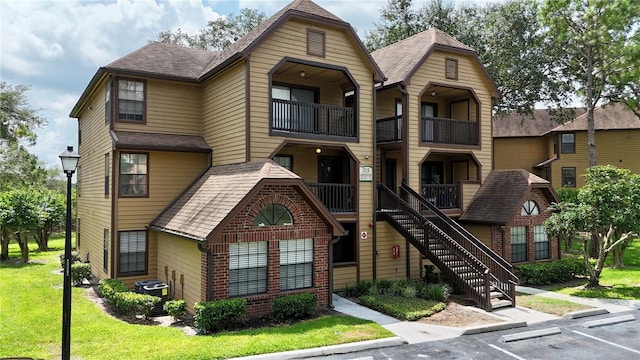 315 Lakepointe Dr Unit 101, Altamonte Springs, FL 32701 - view of front of house with uncovered parking, a balcony, a front lawn, and a shingled roof