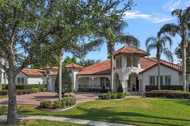 5909 Oxford Moor Blvd, Windermere, FL 34786 - mediterranean / spanish home with a tiled roof, curved driveway, stucco siding, and a front lawn