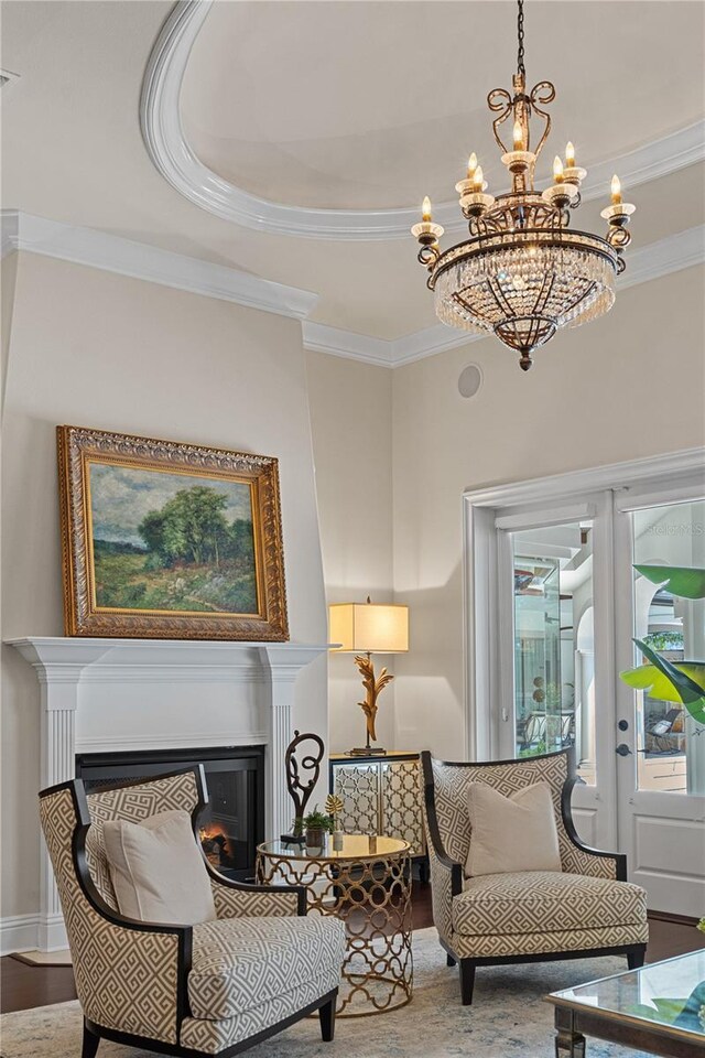 5909 Oxford Moor Blvd, Windermere, FL 34786 - sitting room featuring ornamental molding, a glass covered fireplace, a chandelier, a tray ceiling, and wood finished floors