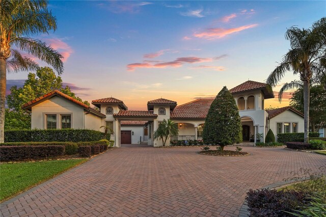 5909 Oxford Moor Blvd, Windermere, FL 34786 - mediterranean / spanish home with curved driveway, stucco siding, a tiled roof, and an attached garage