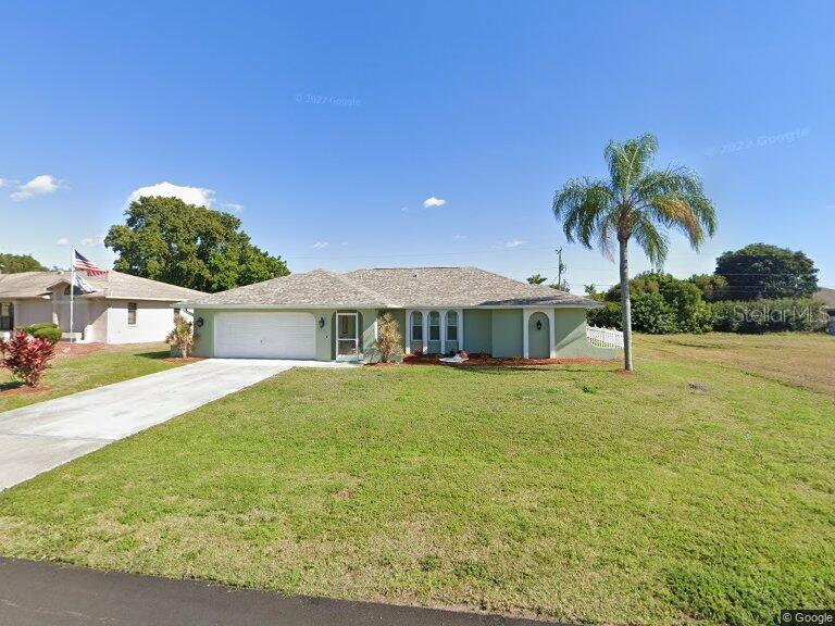 ranch-style house featuring an attached garage, a front lawn, and concrete driveway