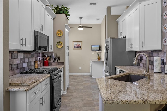 kitchen with black appliances, a sink, a ceiling fan, decorative backsplash, and baseboards