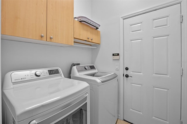 clothes washing area featuring separate washer and dryer and cabinet space
