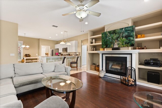 1428 Lucky Pennie Way, Apopka, FL 32712 - living room featuring wood finished floors, a tiled fireplace, a ceiling fan, recessed lighting, and a chandelier