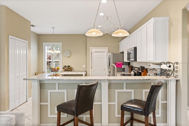 1428 Lucky Pennie Way, Apopka, FL 32712 - kitchen with appliances with stainless steel finishes, a chandelier, light stone counters, white cabinetry, and a peninsula