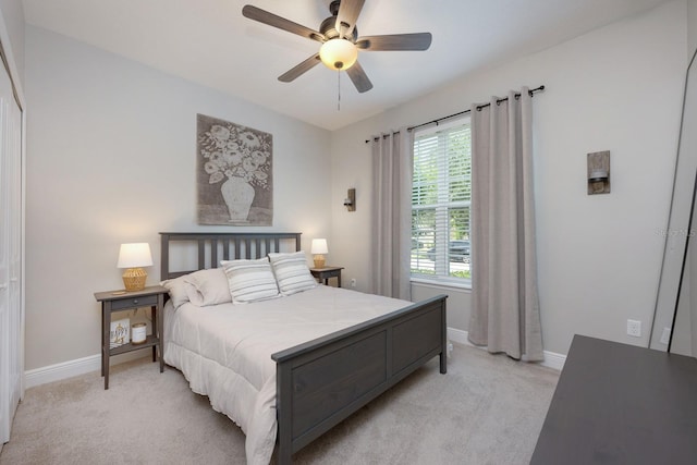bedroom featuring light colored carpet, baseboards, and a ceiling fan