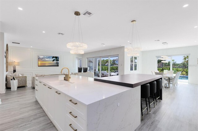 300 Muirfield Loop, Reunion, FL 34747 - kitchen featuring a sink, a chandelier, a large island, light wood-style flooring, and recessed lighting