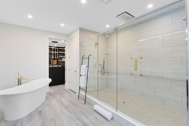 300 Muirfield Loop, Reunion, FL 34747 - full bathroom with a shower stall, a walk in closet, a freestanding bath, recessed lighting, and wood finished floors