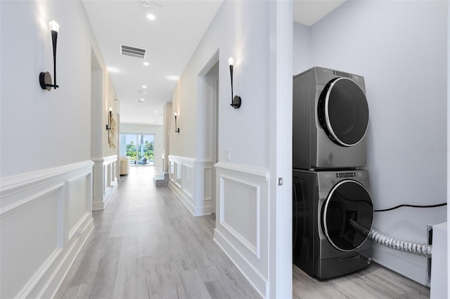 300 Muirfield Loop, Reunion, FL 34747 - laundry room with stacked washer and clothes dryer, light wood finished floors, a wainscoted wall, recessed lighting, and a decorative wall