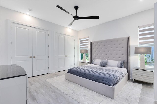 300 Muirfield Loop, Reunion, FL 34747 - bedroom featuring two closets, light wood-type flooring, multiple windows, and a ceiling fan