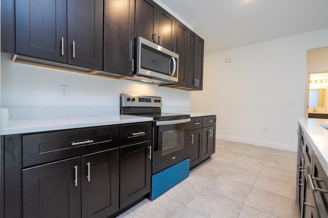 15998 SW 33rd Avenue Rd, Ocala, FL 34473 - kitchen with stainless steel microwave, range with electric stovetop, light countertops, light tile patterned floors, and baseboards