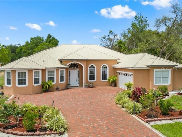 view of front of property with an attached garage, stucco siding, and decorative driveway