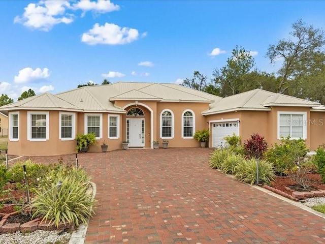 view of front facade featuring stucco siding, an attached garage, and decorative driveway