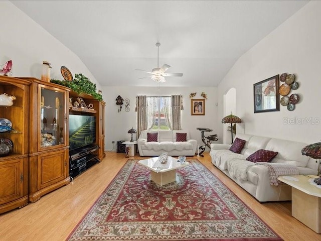 living room featuring vaulted ceiling, light wood-style floors, ceiling fan, and arched walkways