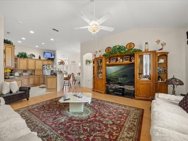 living room with light wood-style floors, a ceiling fan, arched walkways, and recessed lighting