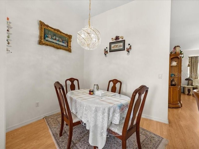 dining room with light wood finished floors, a chandelier, and baseboards