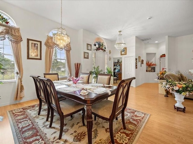 dining space featuring a chandelier, light wood-style flooring, and baseboards