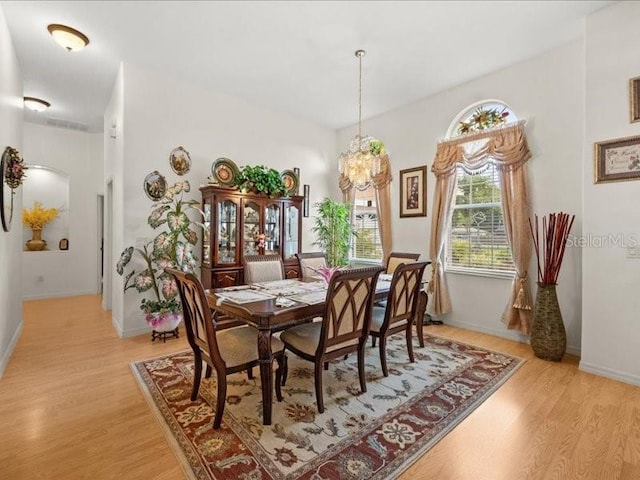 dining space featuring light wood finished floors, a chandelier, and baseboards
