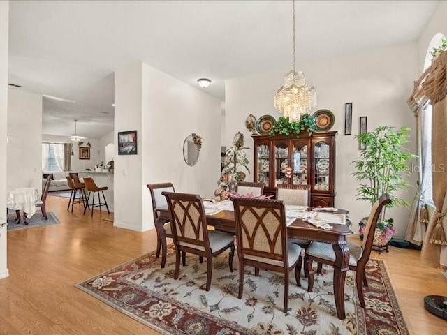 dining space with a chandelier, wood finished floors, and baseboards