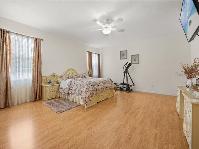 bedroom featuring light wood finished floors, a ceiling fan, and baseboards