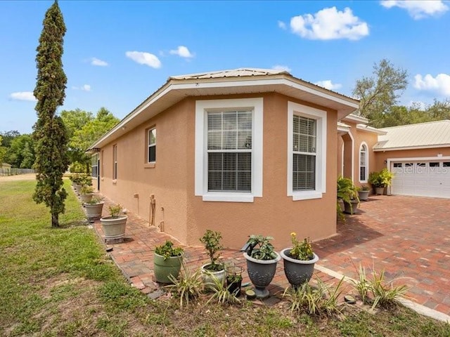 view of side of property with stucco siding, a yard, a garage, and driveway