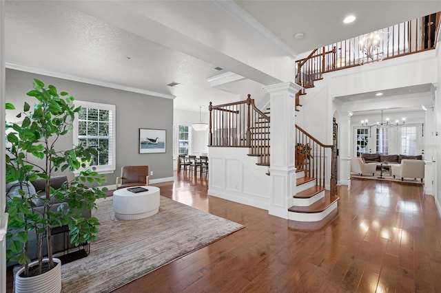 living room with stairway, a chandelier, hardwood / wood-style flooring, ornamental molding, and ornate columns
