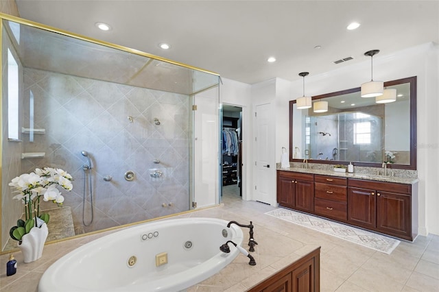 bathroom featuring a shower stall, a jetted tub, a spacious closet, double vanity, and tile patterned floors