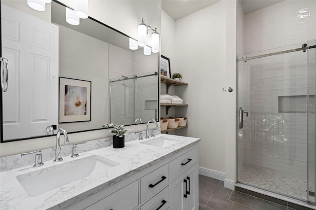 full bathroom with a shower stall, double vanity, baseboards, and tile patterned flooring